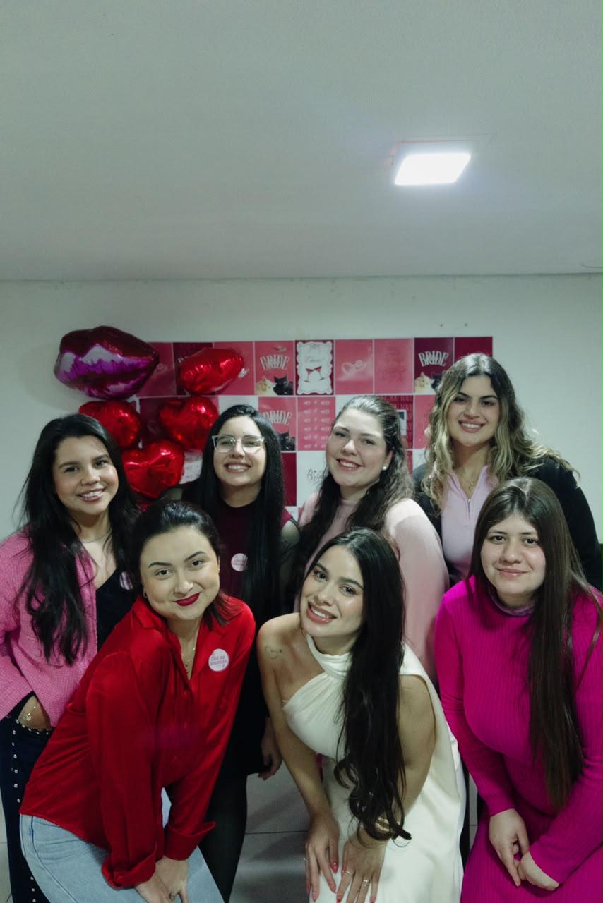 Amigas posando juntas diante de uma decoração com corações