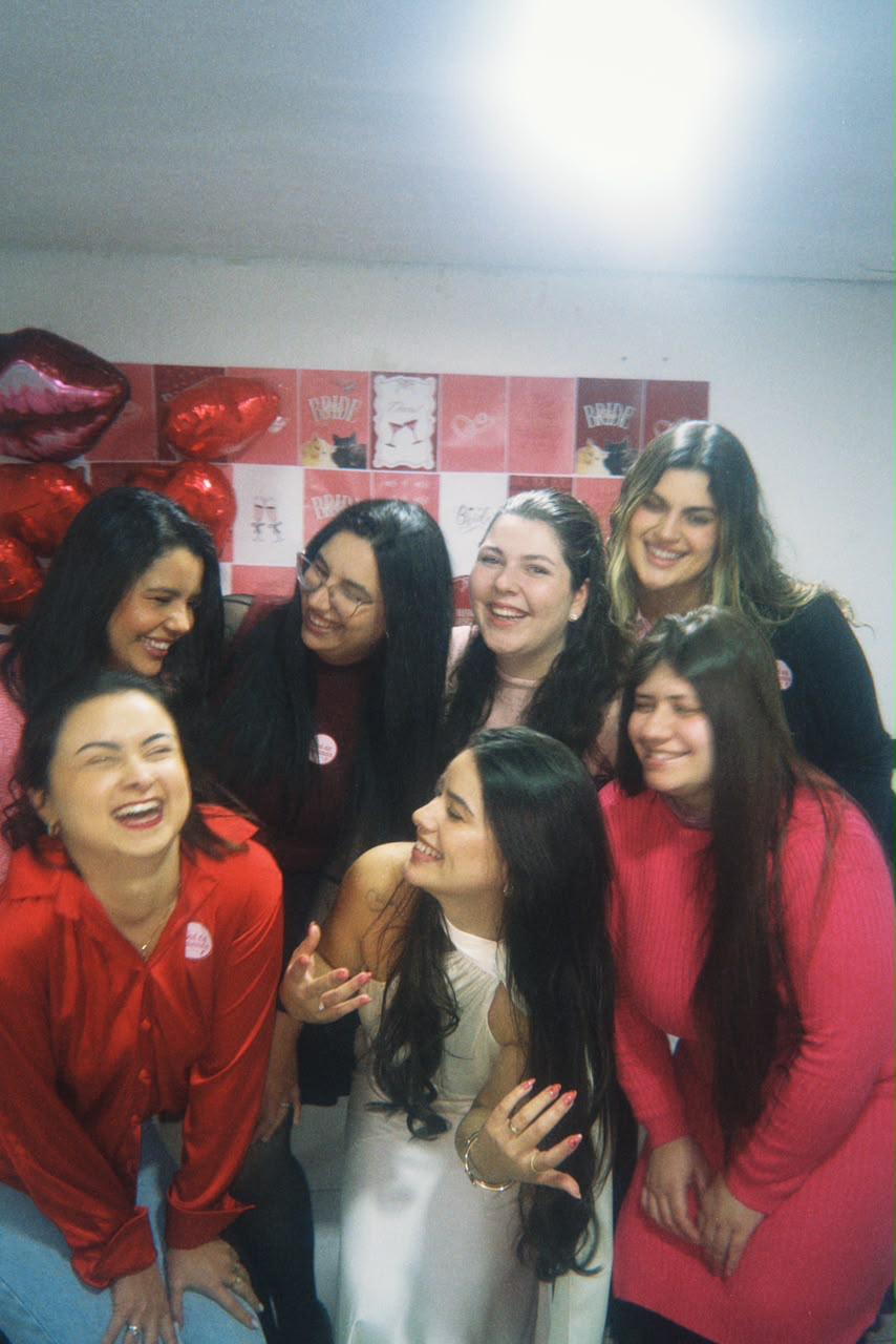 Amigas rindo juntas diante de uma decoração com corações